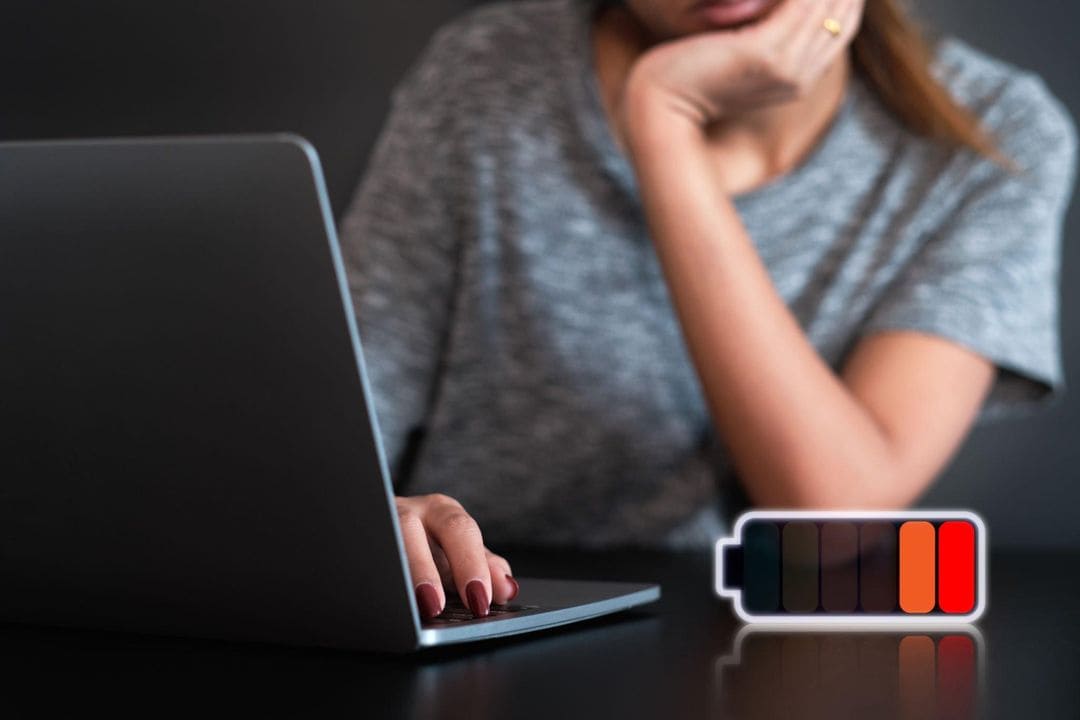 Personne devant un ordinateur portable, avec une icône de batterie.